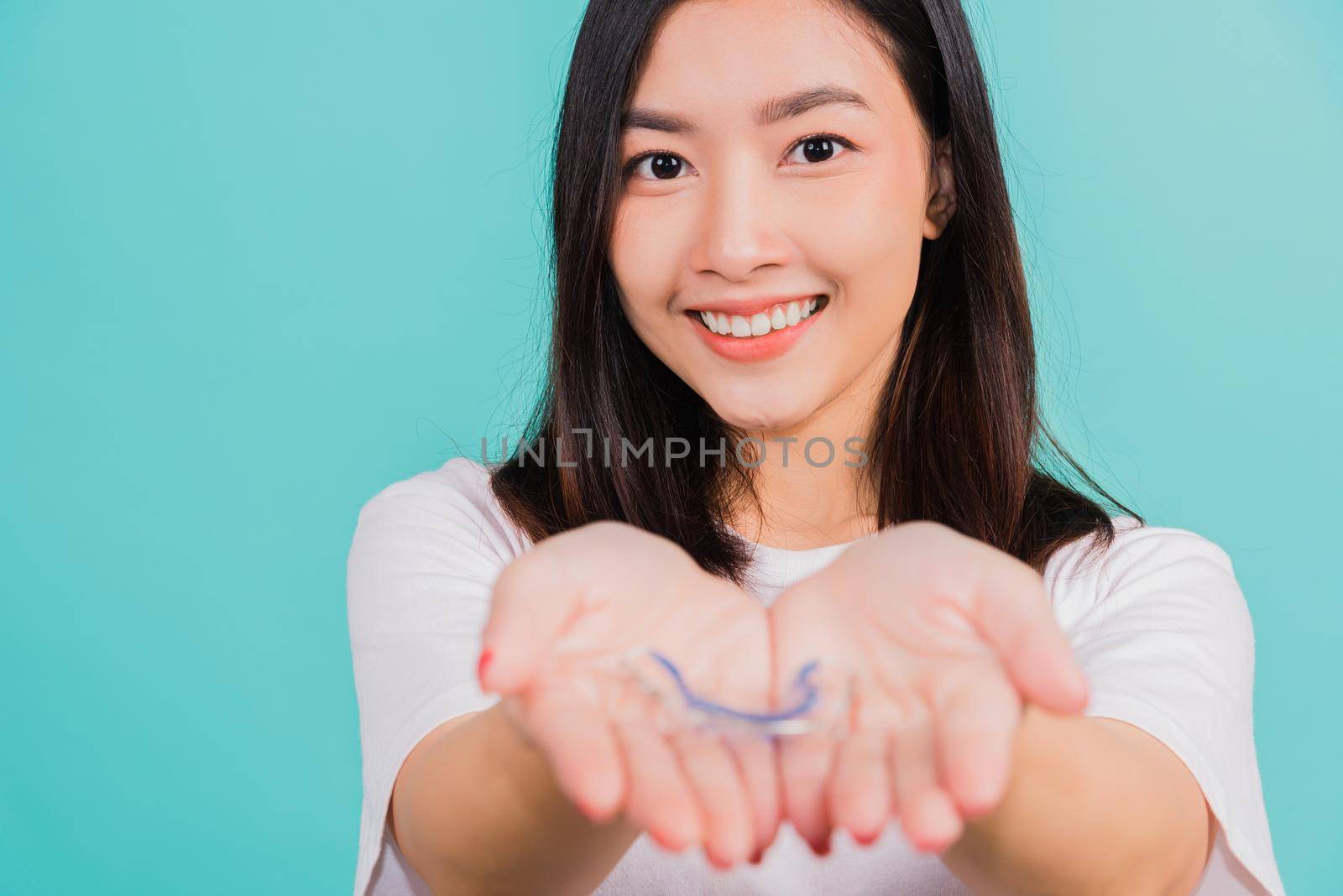 woman smiling holding silicone orthodontic retainers for teeth on hand palm by Sorapop