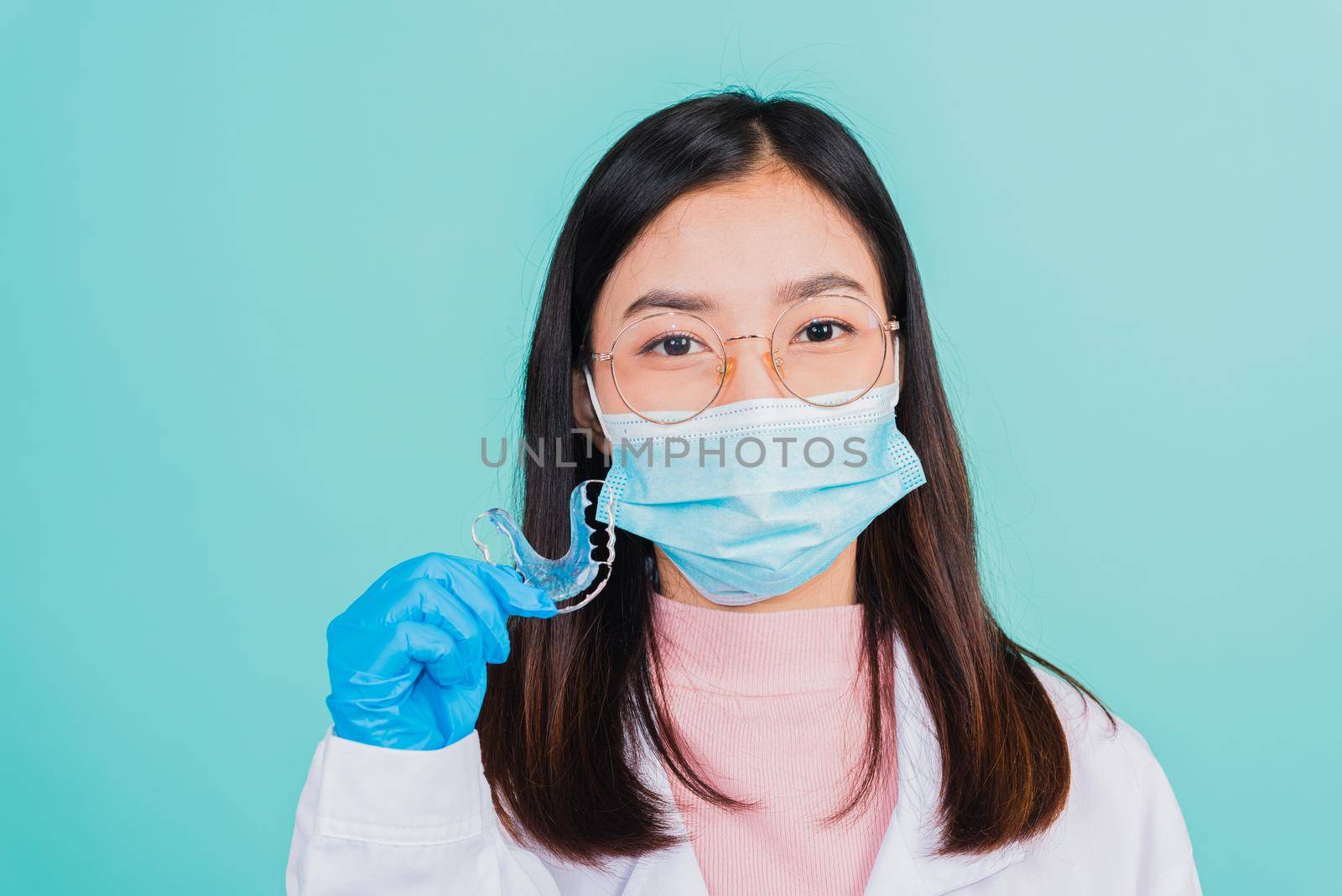 Asian beautiful woman dentist holding silicone orthodontic retainers for teeth on hand isolated blue background, Teeth retaining tools after removable braces, Orthodontics dental healthy care concept