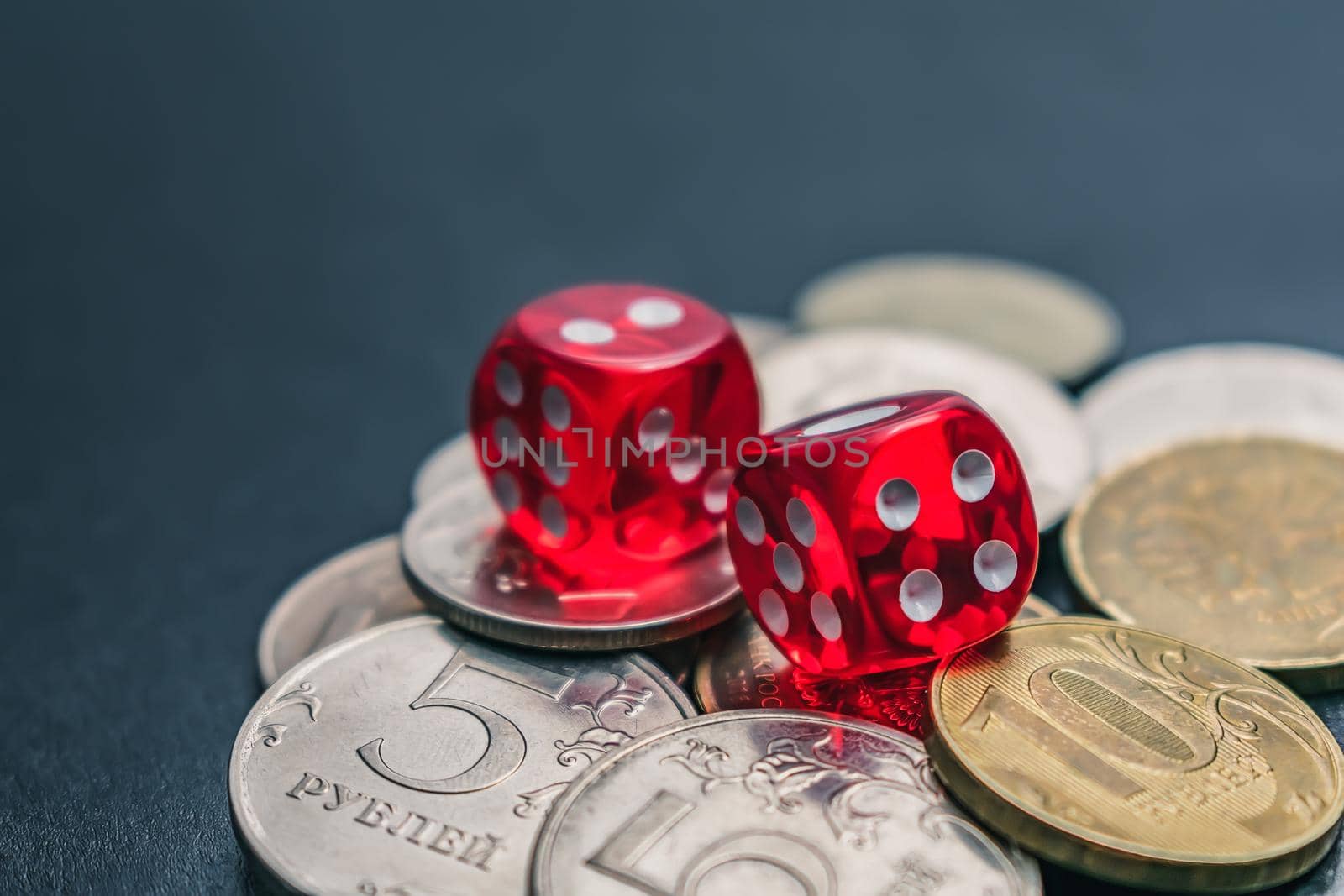 Red dice lie on different coins won at casino bets