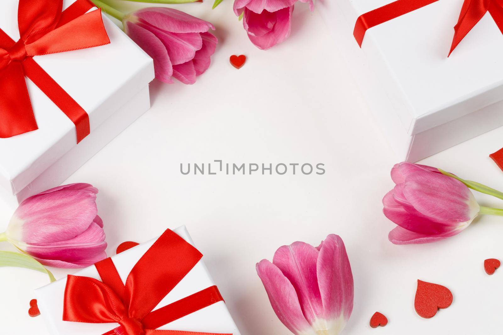 Pink tulip flowers gifts and red hearts composition on white background top view with copy space. Valentine's day, birthday, wedding, Mother's day concept. Copy space
