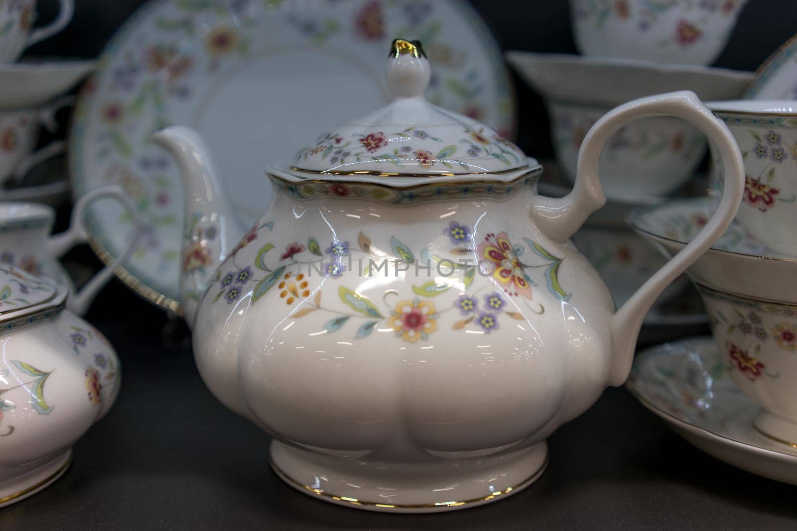 Porcelain teapot in the background of dishes and the dark background