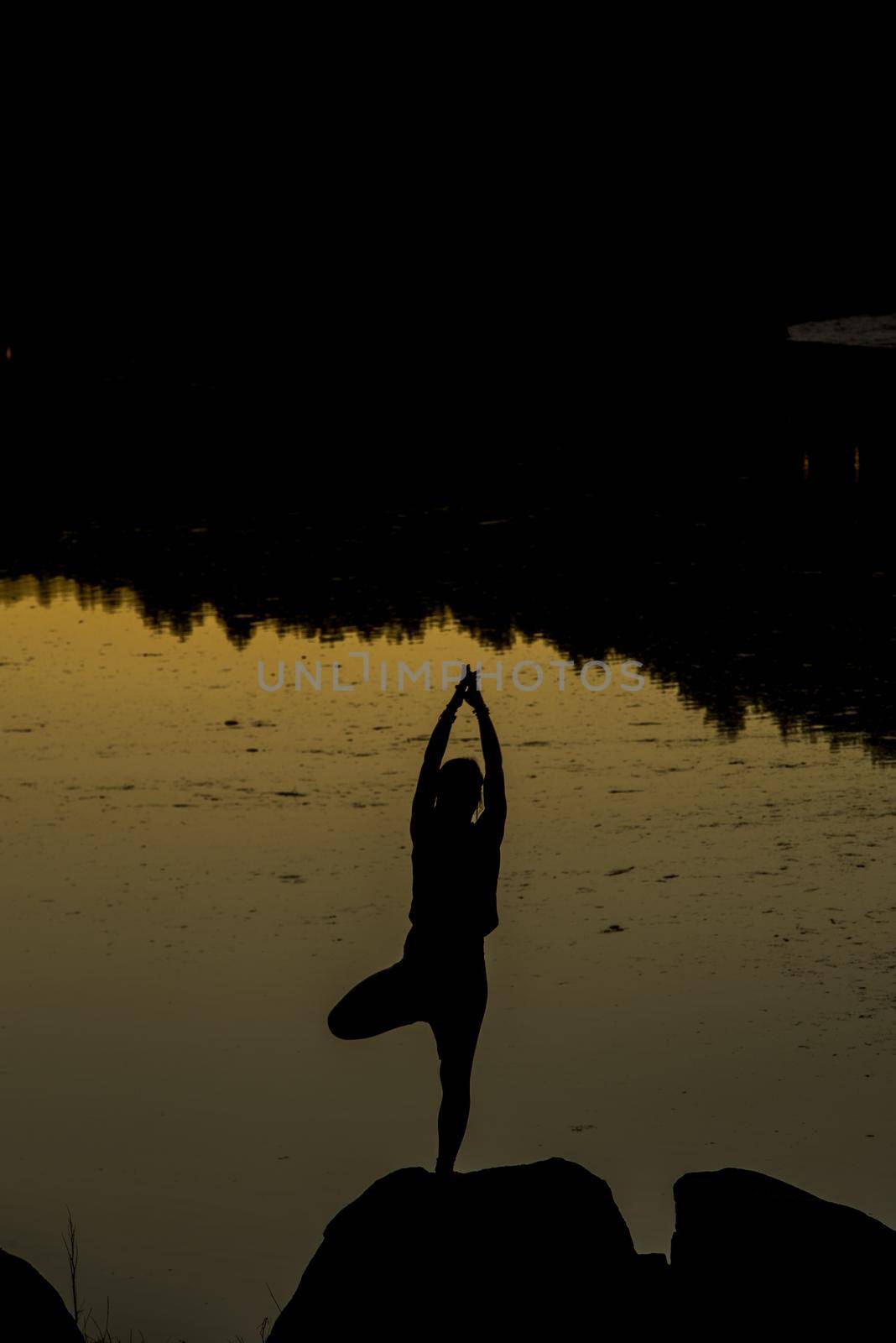 Silhouettes of a woman doing yoga at sunset.