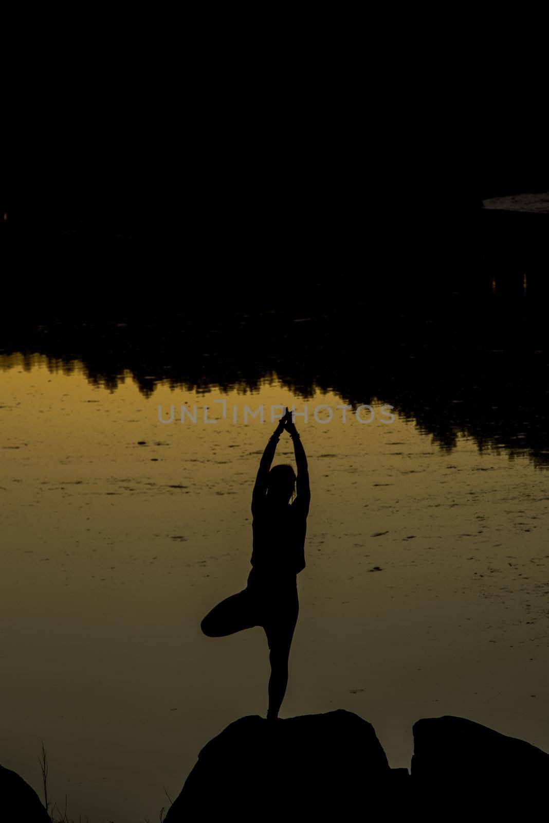 Silhouettes of a woman doing yoga at sunset by martinscphoto