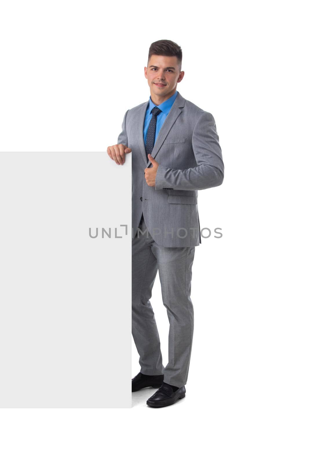 Full length portrait of young man in suit showing banner whiteboard sign isolated on white background