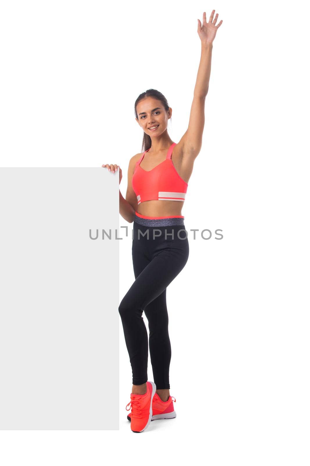 Healthy hispanic fitness girl with arm raised holding blank banner isolated on white background