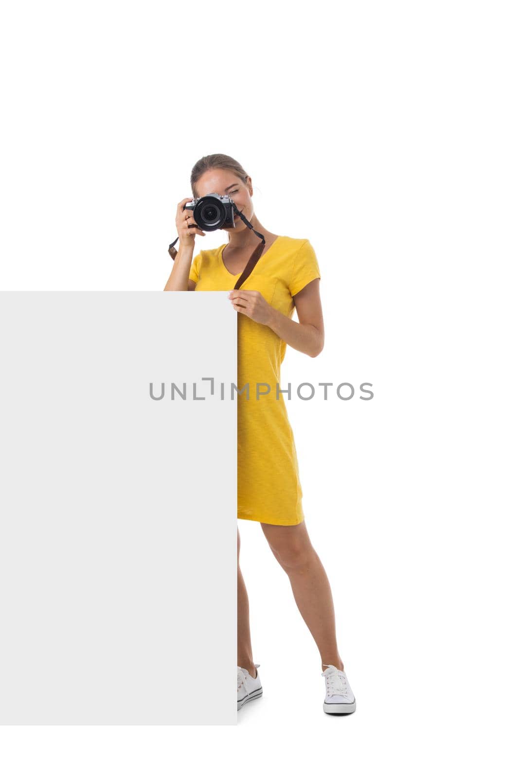 Full length portrait of young beautiful photographer girl with the camera and blank banner isolated on white background