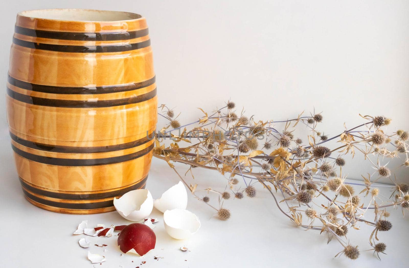 Easter. Still life with eggshells, clay barrel and dried flowers on a white background.