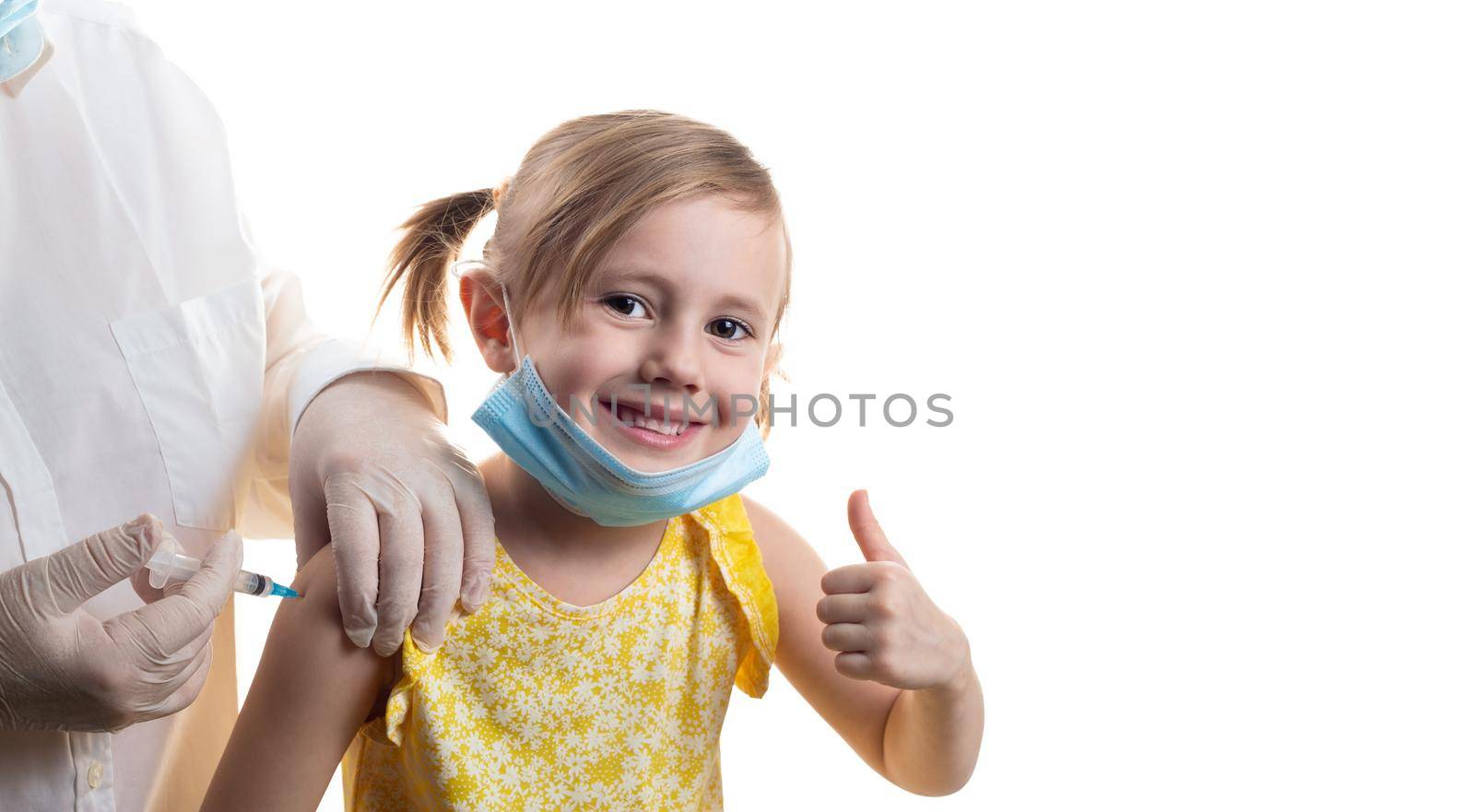 Doctor is vaccinating a young Caucasian girl in yellow dress showing thumb up isolated on white background