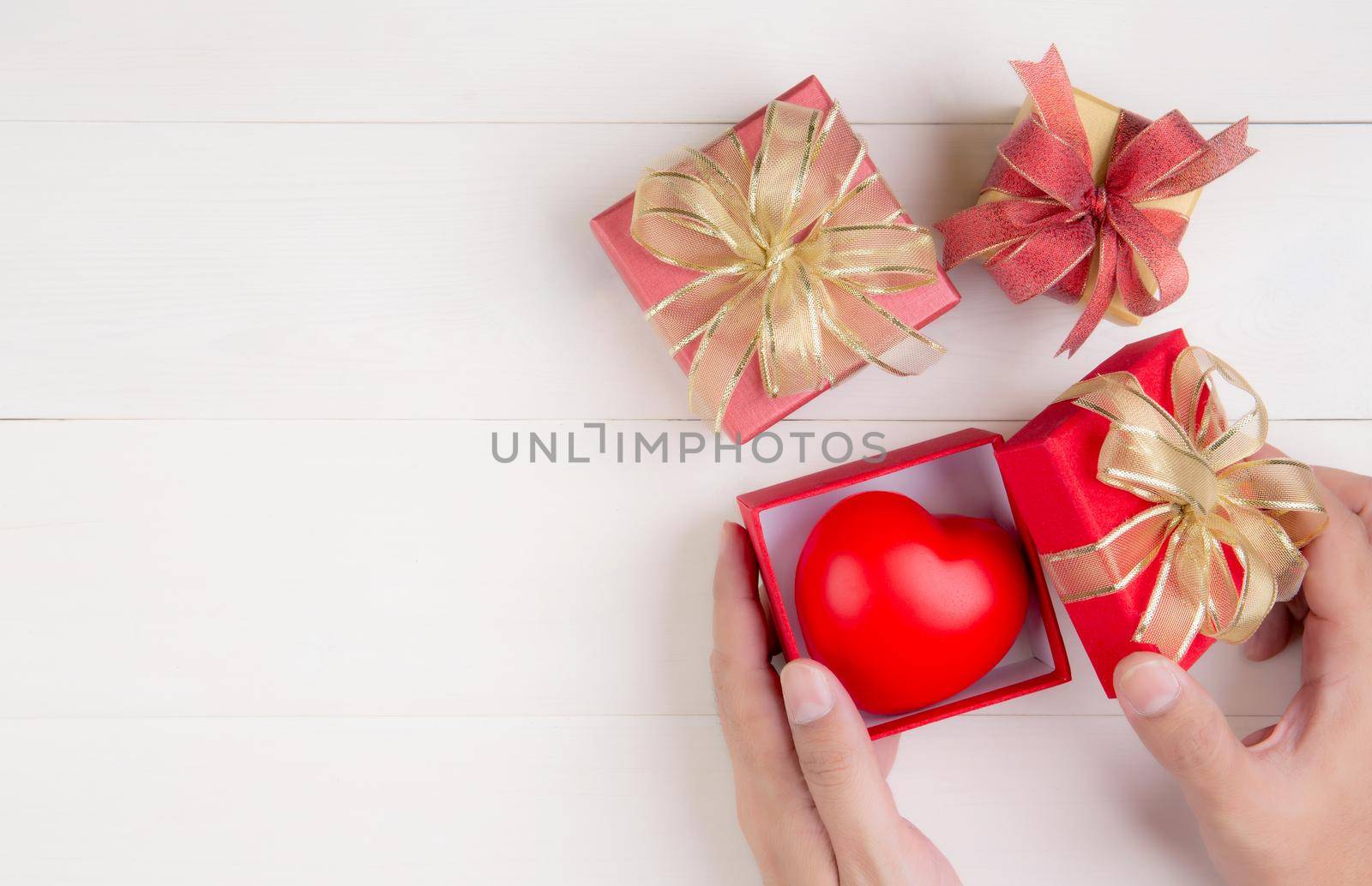 Valentine day, hand open red gift box with heart shape on wooden white background, celebration and anniversary with giving love, presents with romantic and surprise, holiday and festive concept. by nnudoo