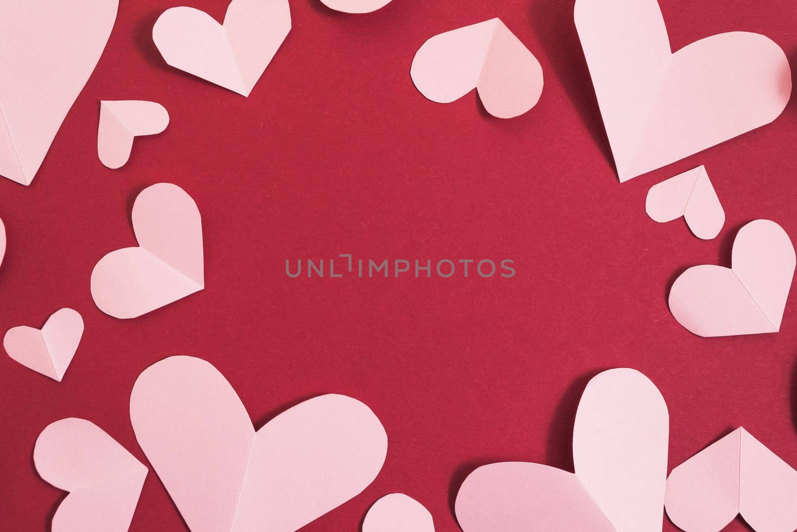 Valentine's day background. Pink hearts laid out in the form of a frame on a burgundy background. Valentine's day concept. Layout for postcards and congratulations. Flat lay, top view, copy space