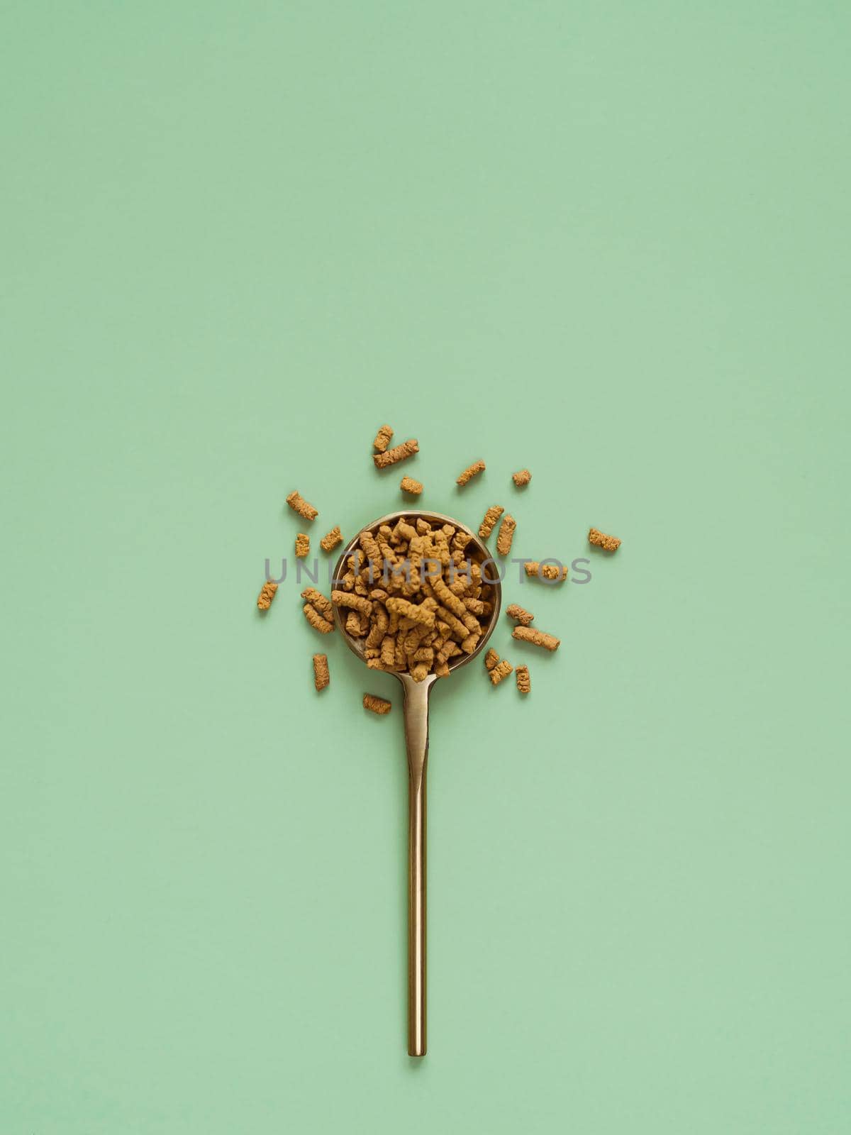 Buckwheat tea in spoon on light green background. Top view of healthy ku qiao or soba tea groats over green paper background. Minimal flat lay tartary buckwheat seeds. Copy space. Vertical