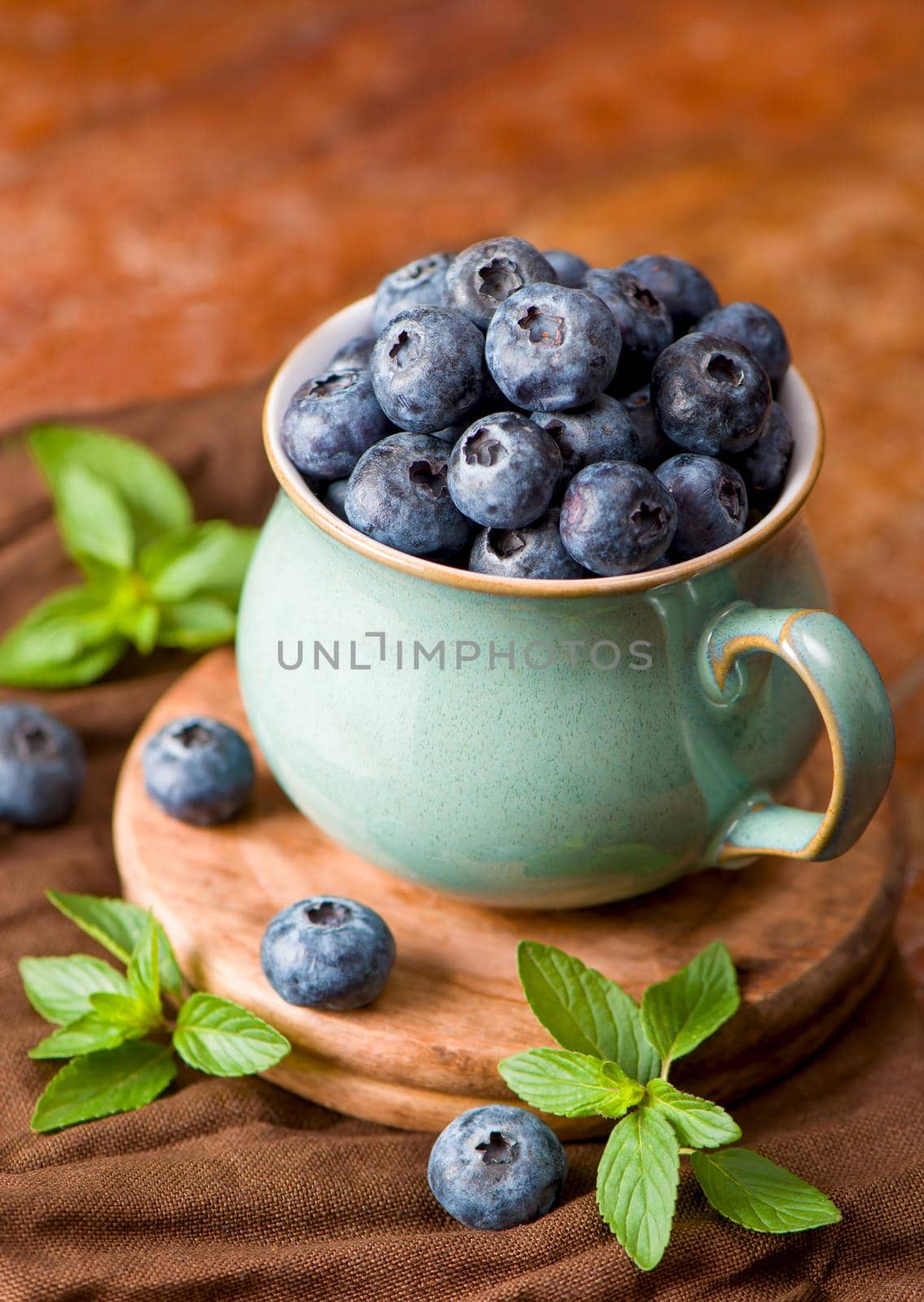 Fresh blueberry in a cup with leaves of mint.