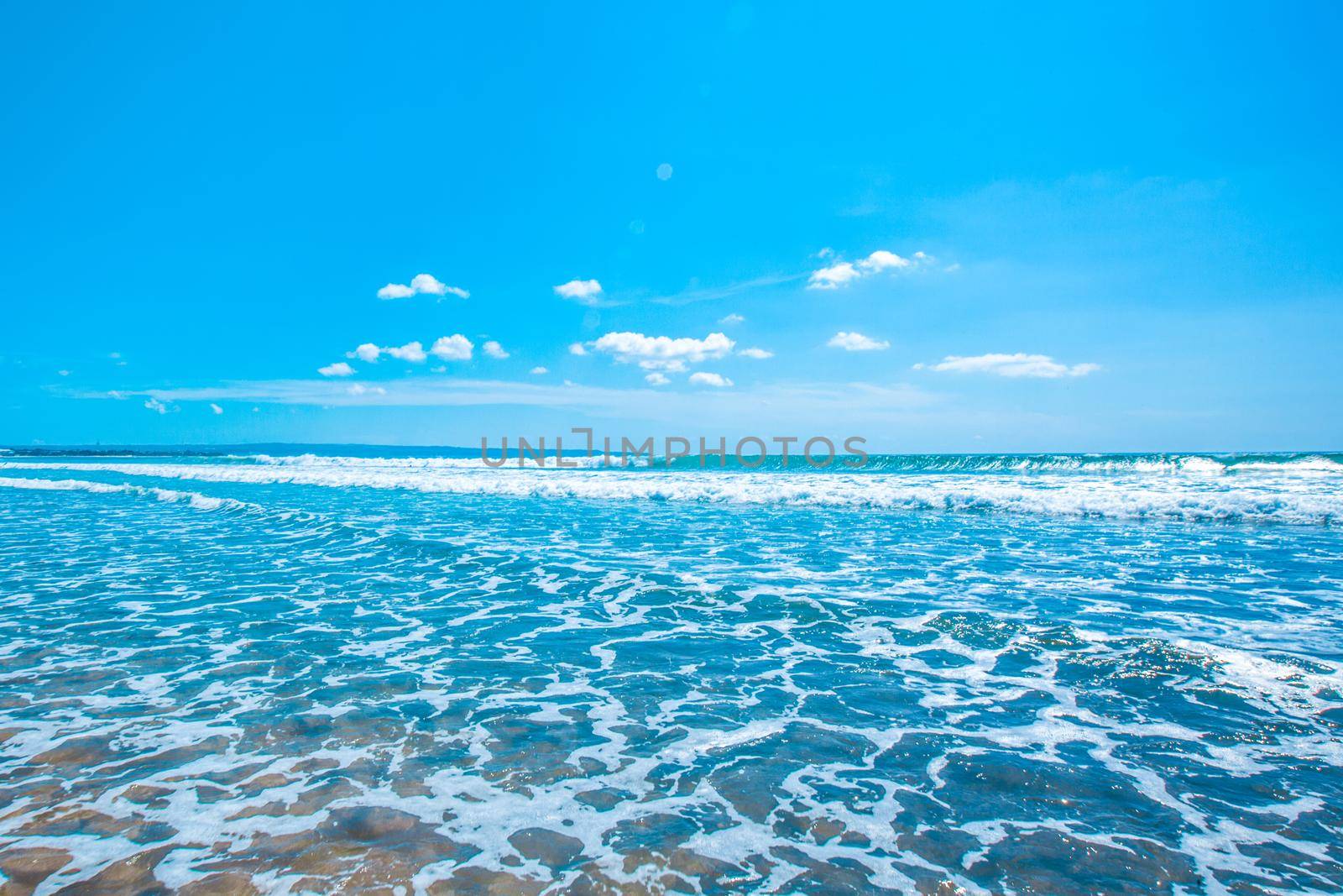 Tropical sea waves surf coming on beach, blue sky over horizon