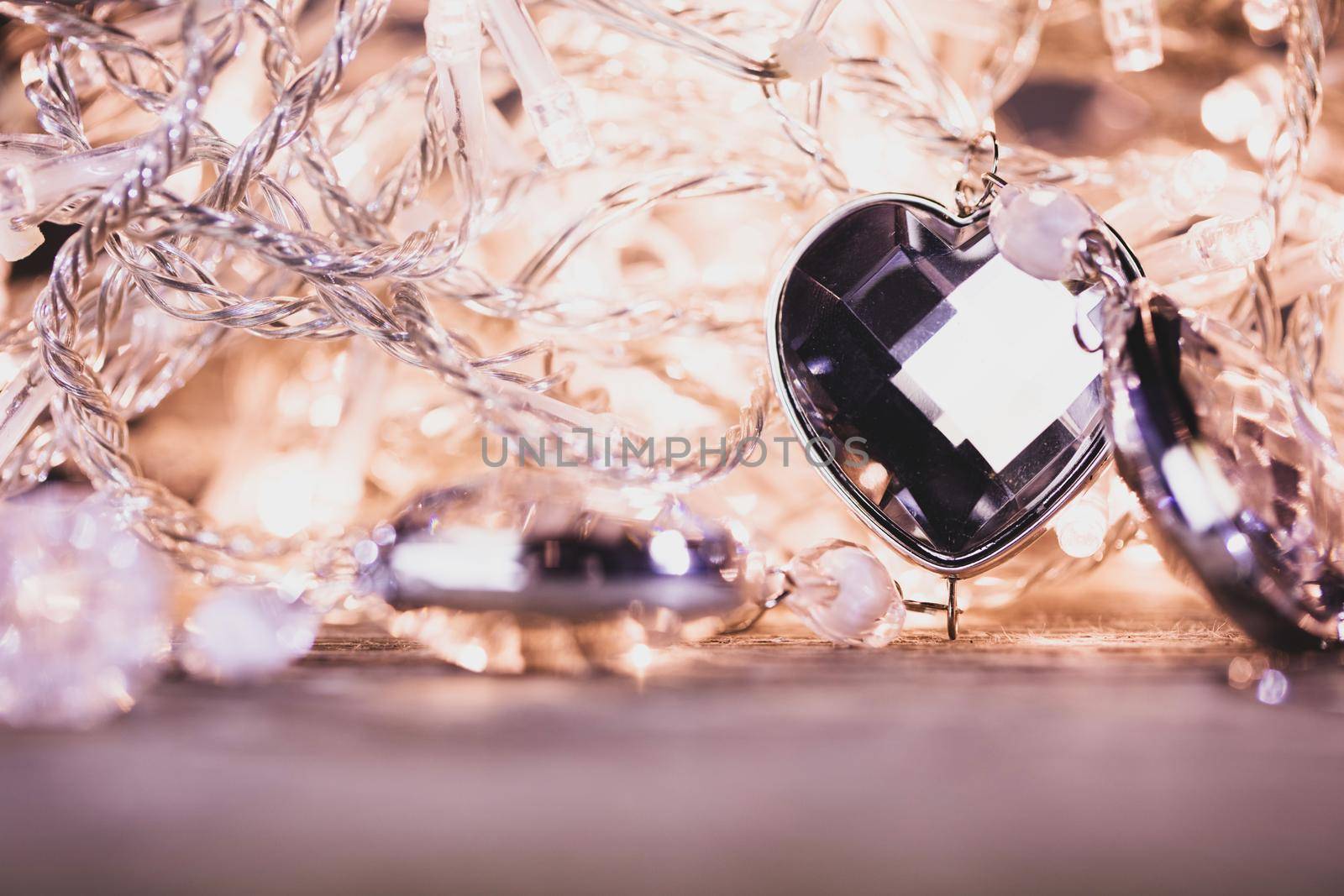 Heart shaped gem stones on golden lights of electric garland with bokeh