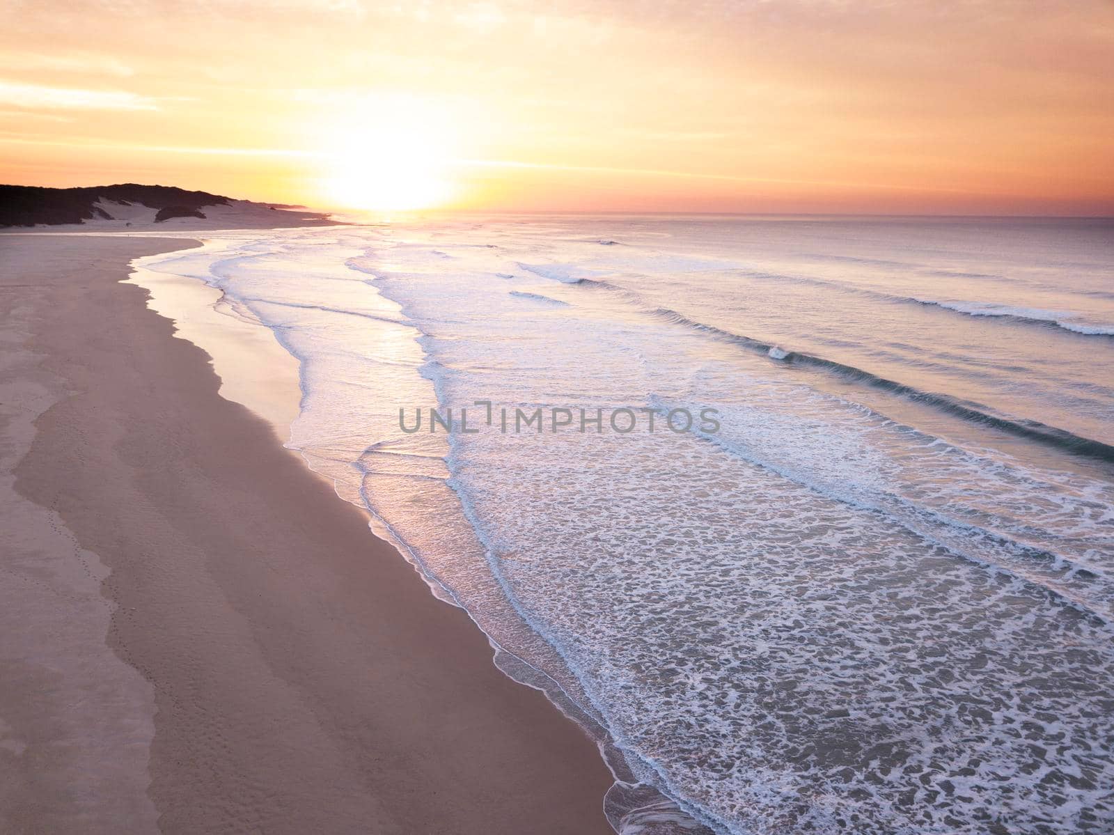 Aerial of sunrise over the ocean and empty beach