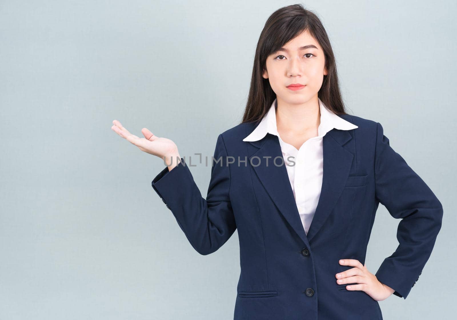 Asian woman in suit open hand palm gestures with empty space isolated on gray background
