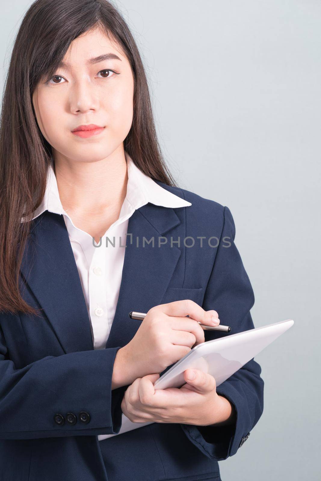 Woman in suit using computer digital tablet isolated on gray background