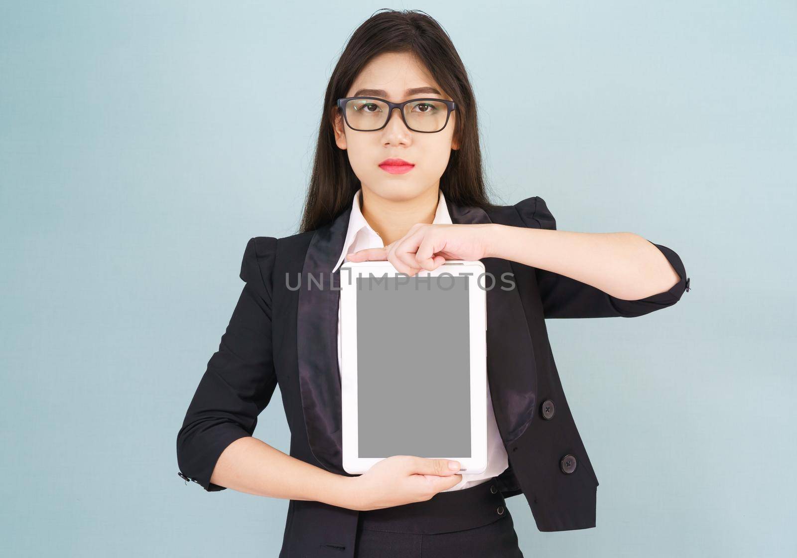 Young asian women in suit holding her digital tablet standing against green background