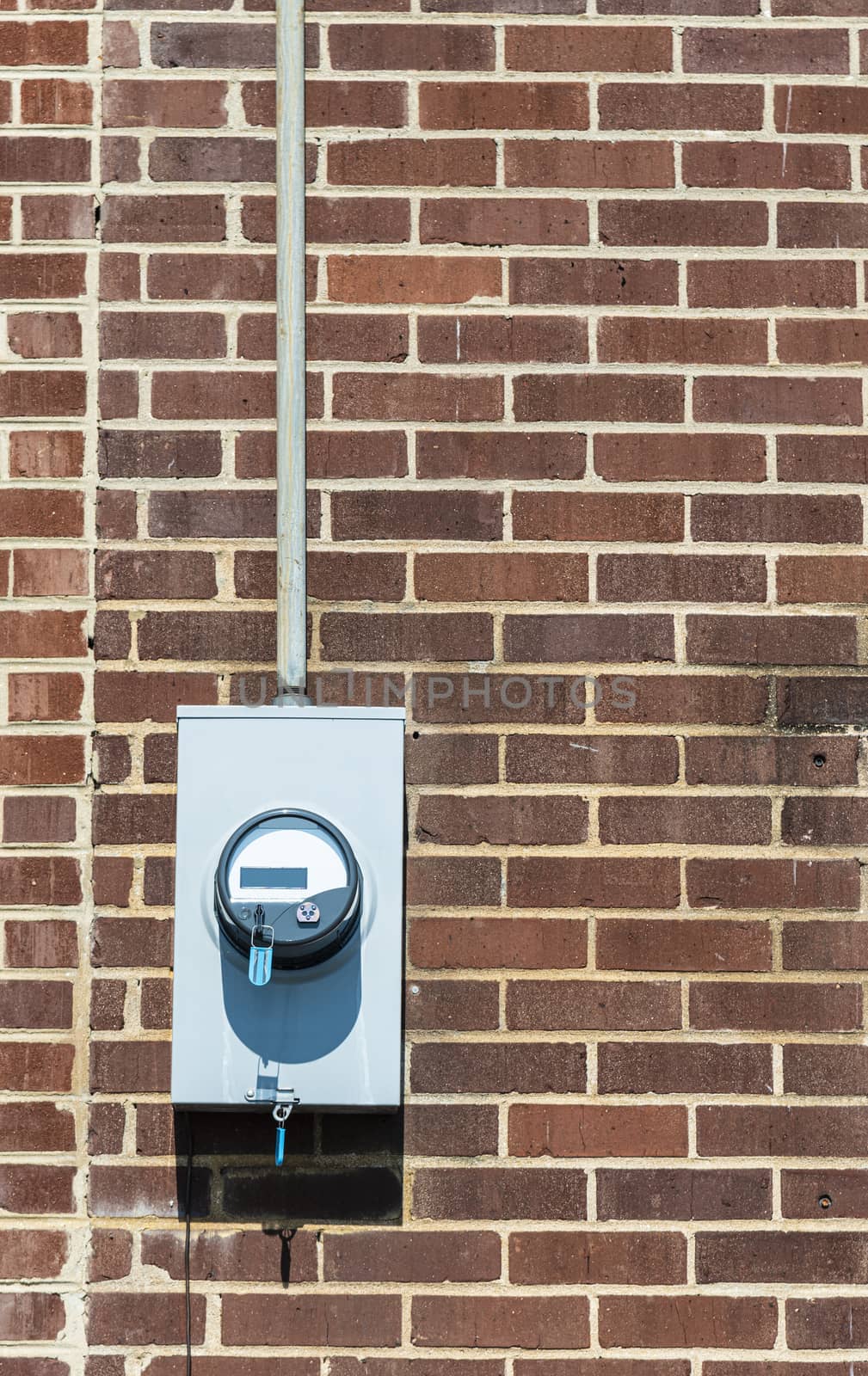 Vertical shot of an electric meter on an old red brick wall.  Copy space.