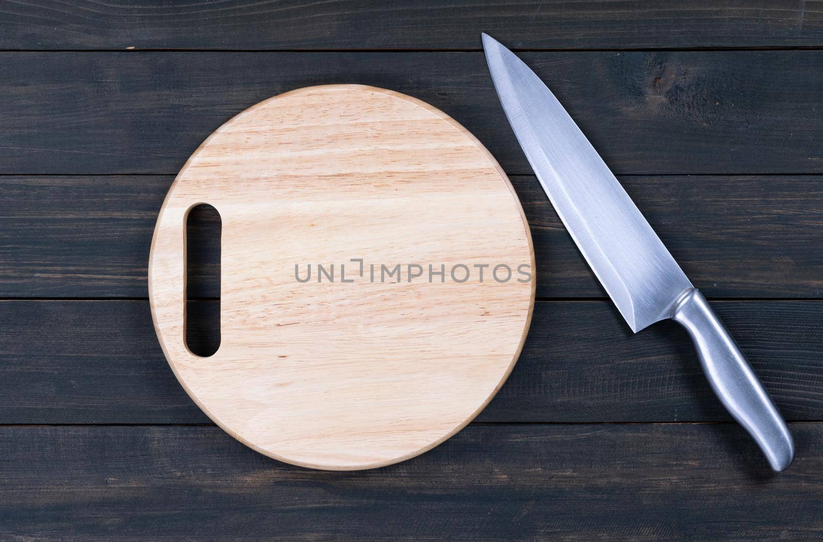 Close up kitchen knife and wooden round empty cutting board on a wooden table