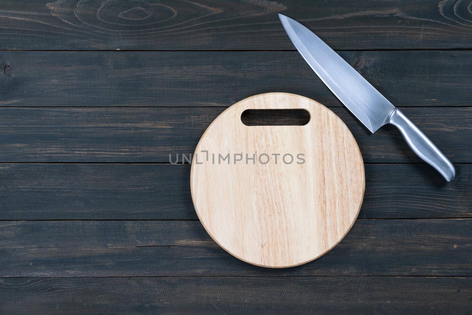 kitchen knife and wooden round empty cutting board on a wooden table close up