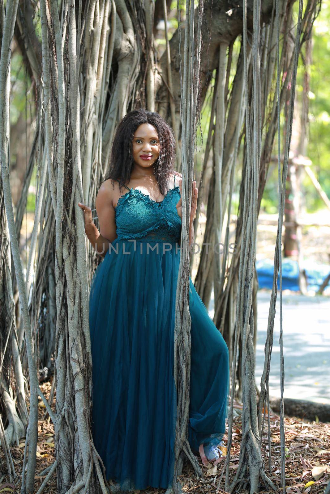 Cheerful young woman standing by tree in the jungle. 