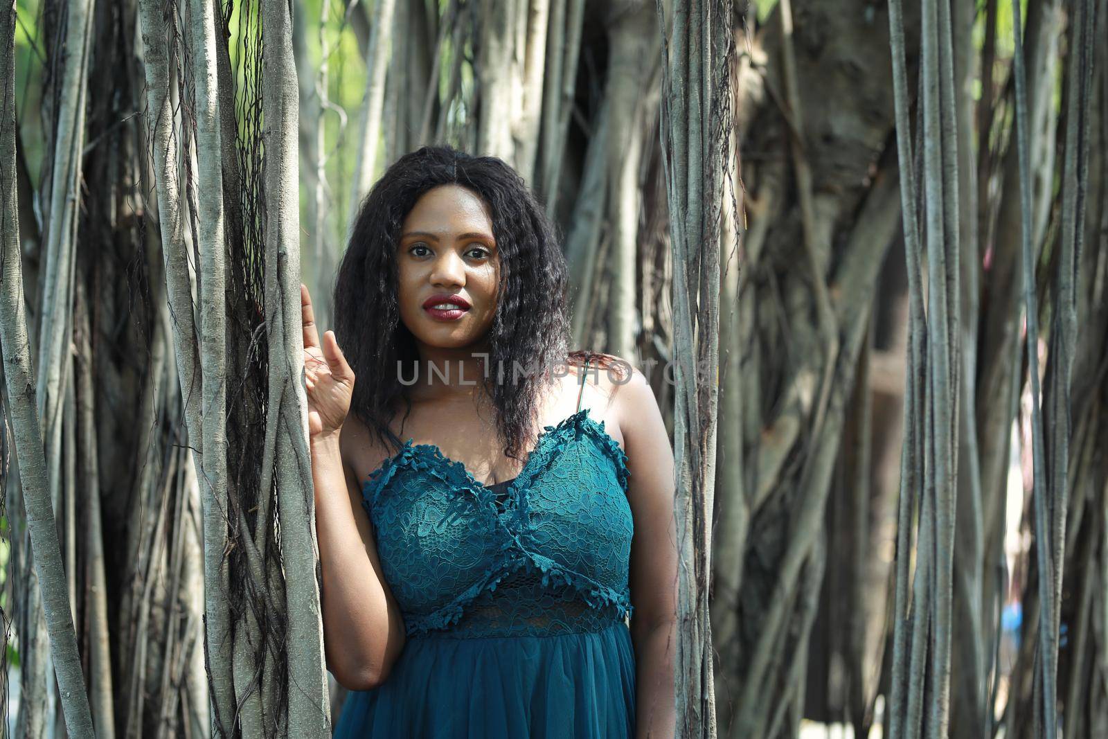 Cheerful young woman standing by tree in the jungle. 