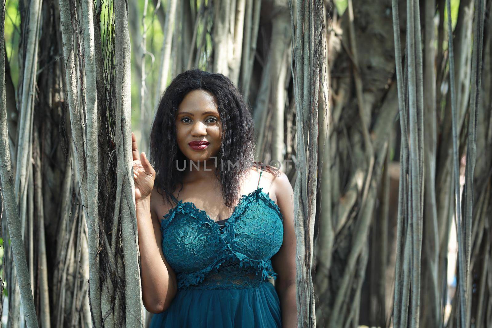 Cheerful young woman standing by tree in the jungle. 