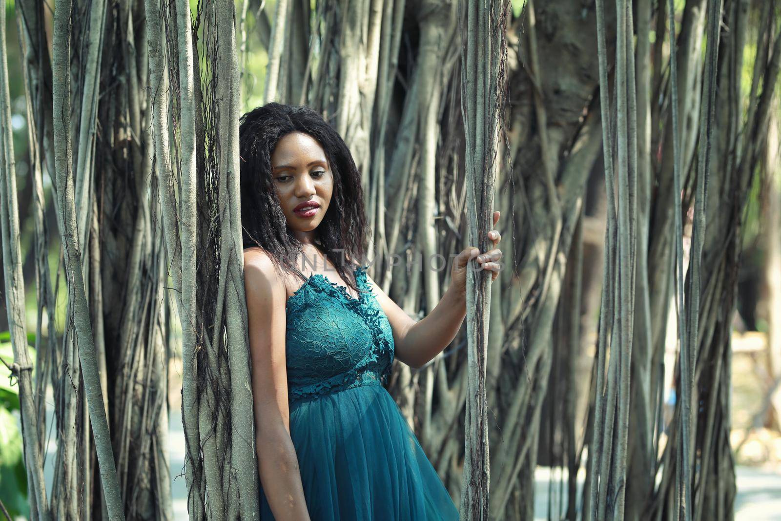 Cheerful young woman standing by tree in the jungle. 