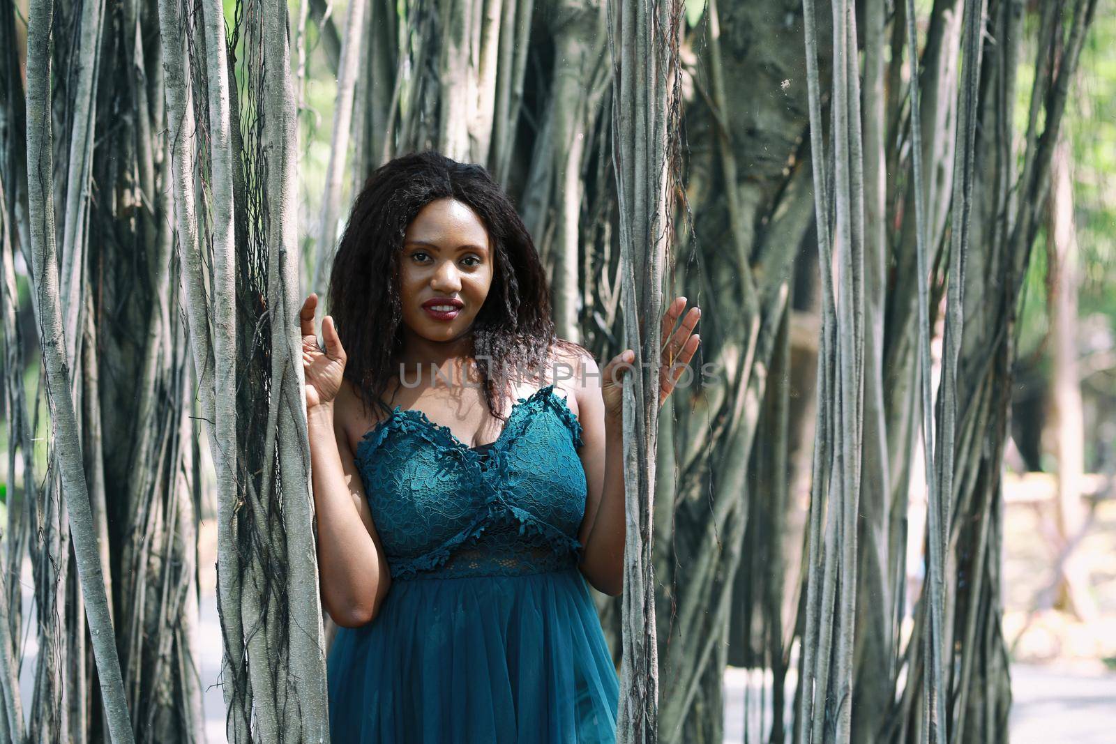 Cheerful young woman standing by tree in the jungle. 
