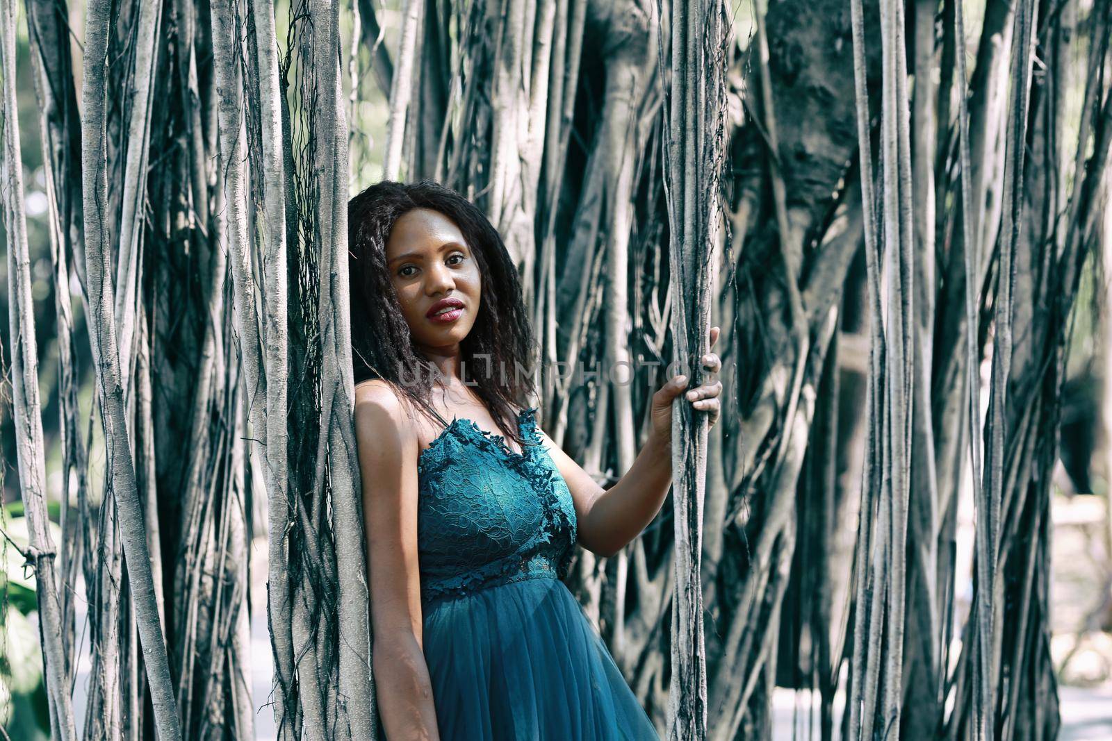 Cheerful young woman standing by tree in the jungle. 