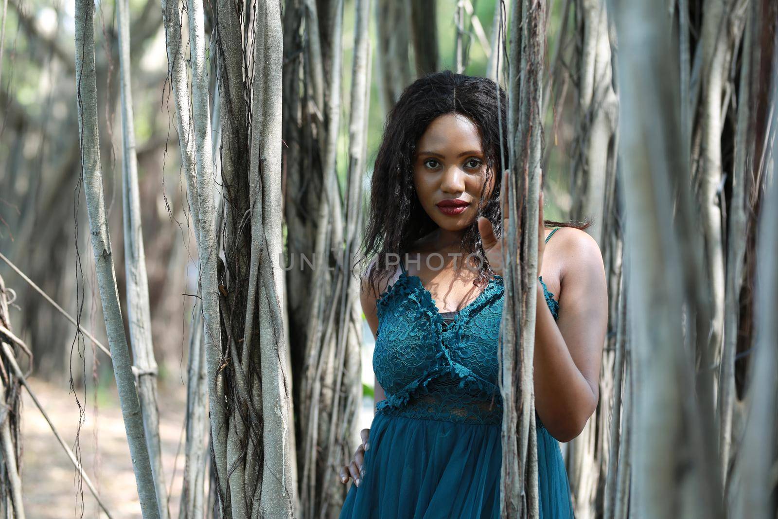 Cheerful young woman standing by tree in the jungle. 