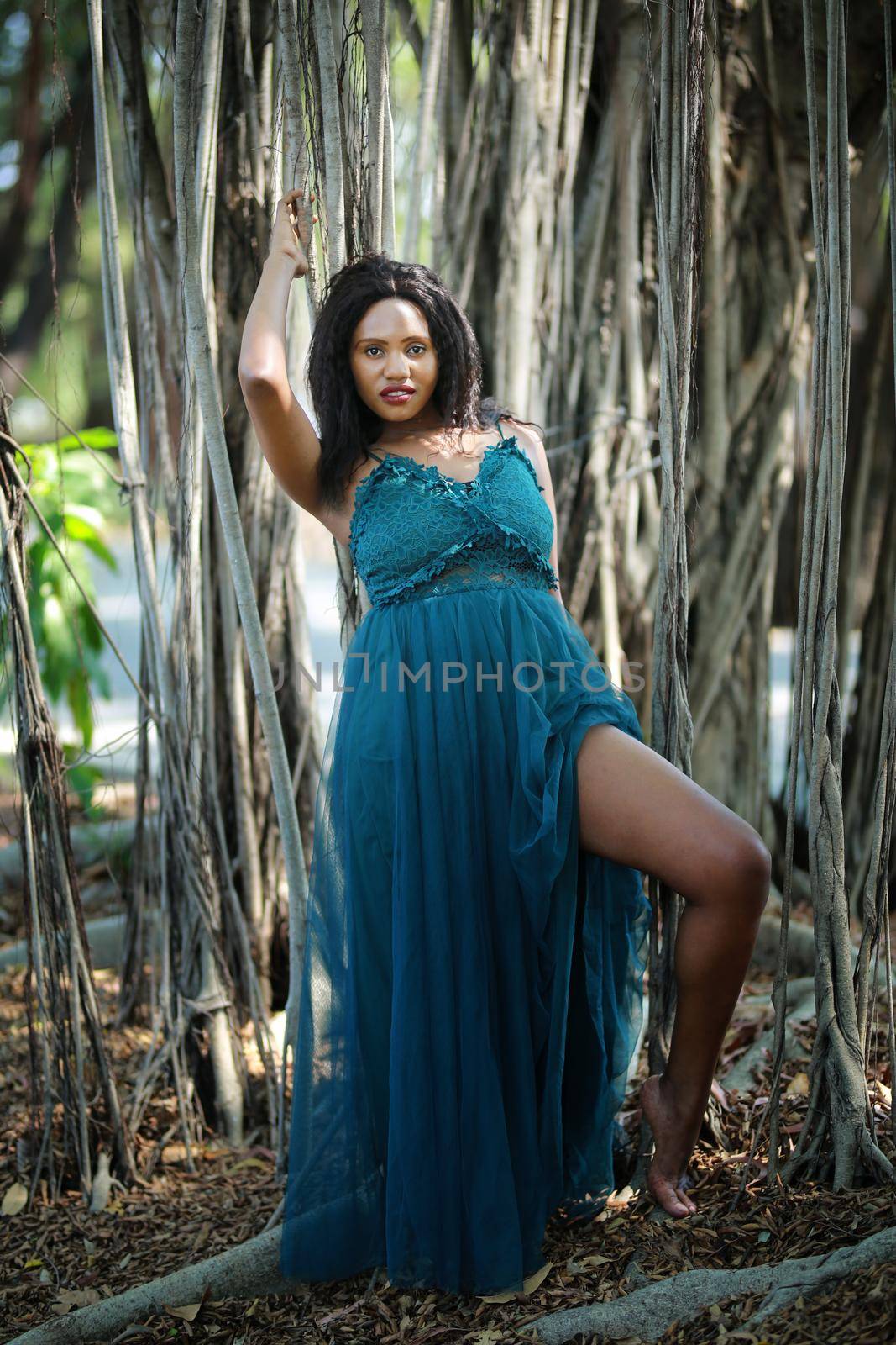 Cheerful young woman standing by tree in the jungle. 