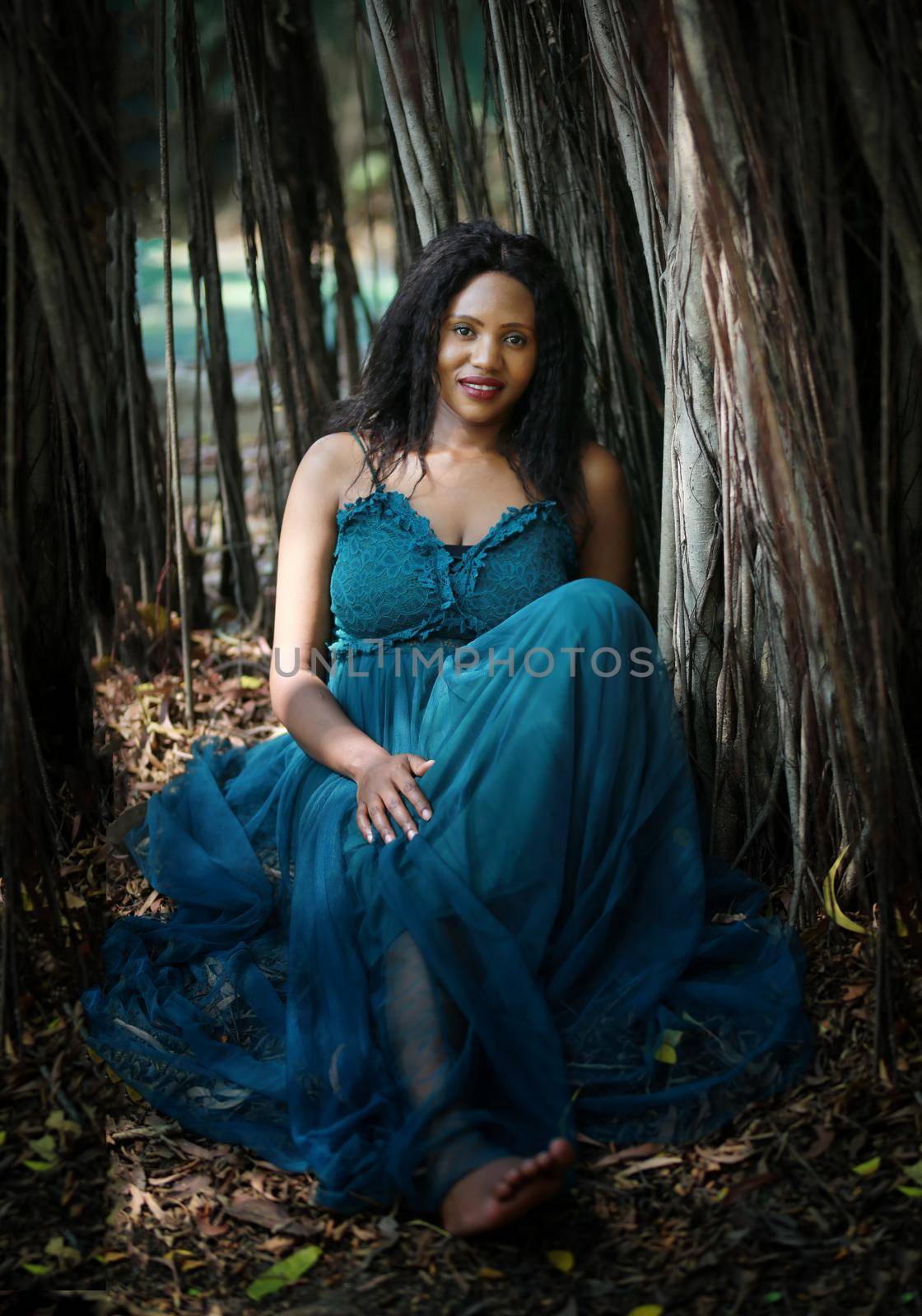 Cheerful young woman standing by tree in the jungle. 