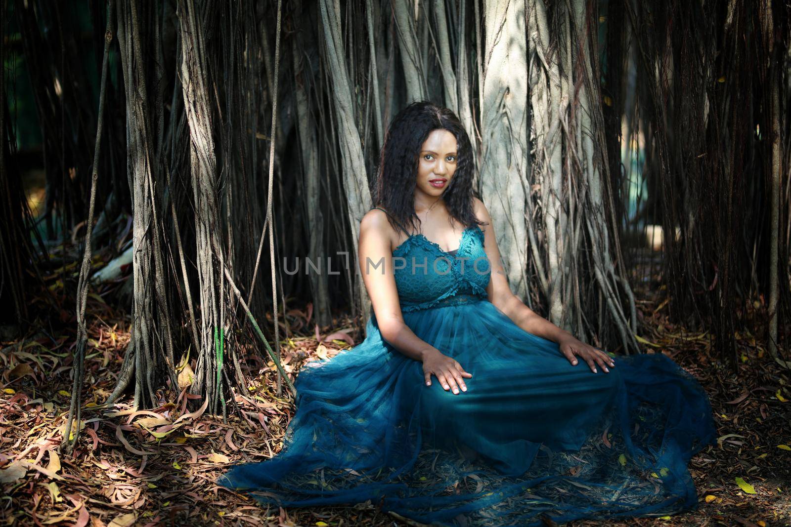 Cheerful young woman standing by tree in the jungle. 