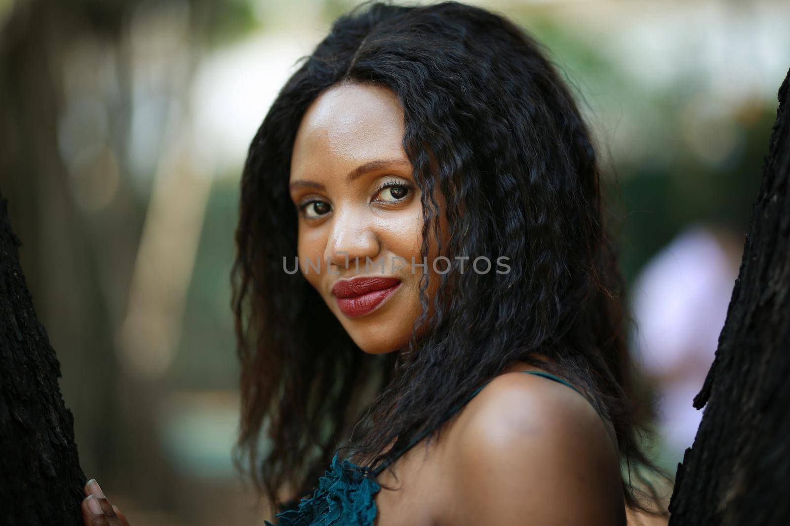 Cheerful young woman standing by tree in the jungle. 