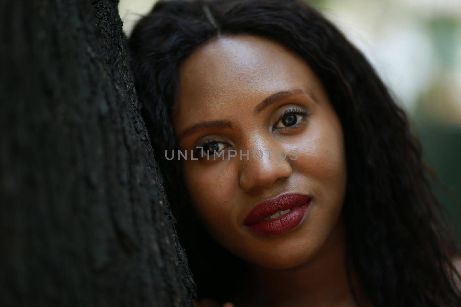 Cheerful young woman standing by tree in the jungle. 