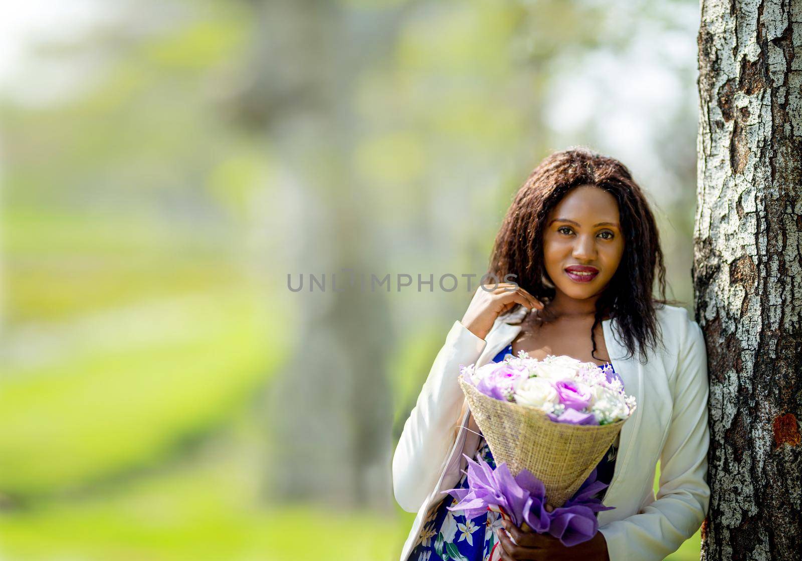 Cheerful young woman standing at outdoor with flower.