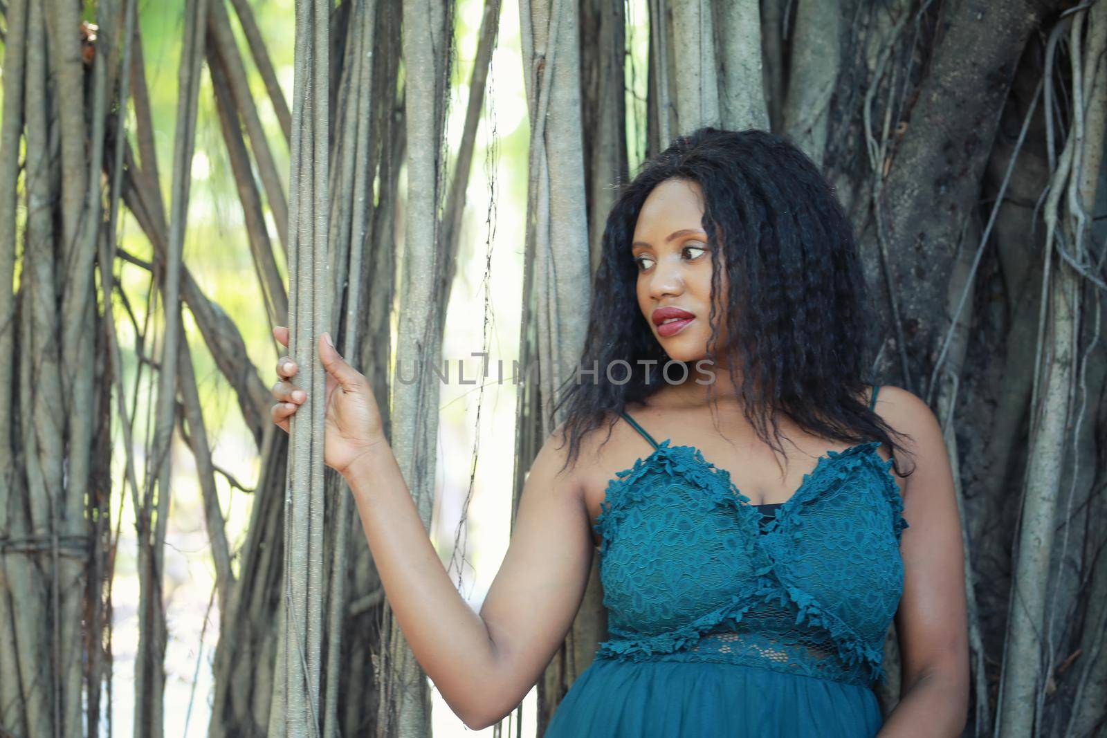 Cheerful young woman standing among tropical garden.