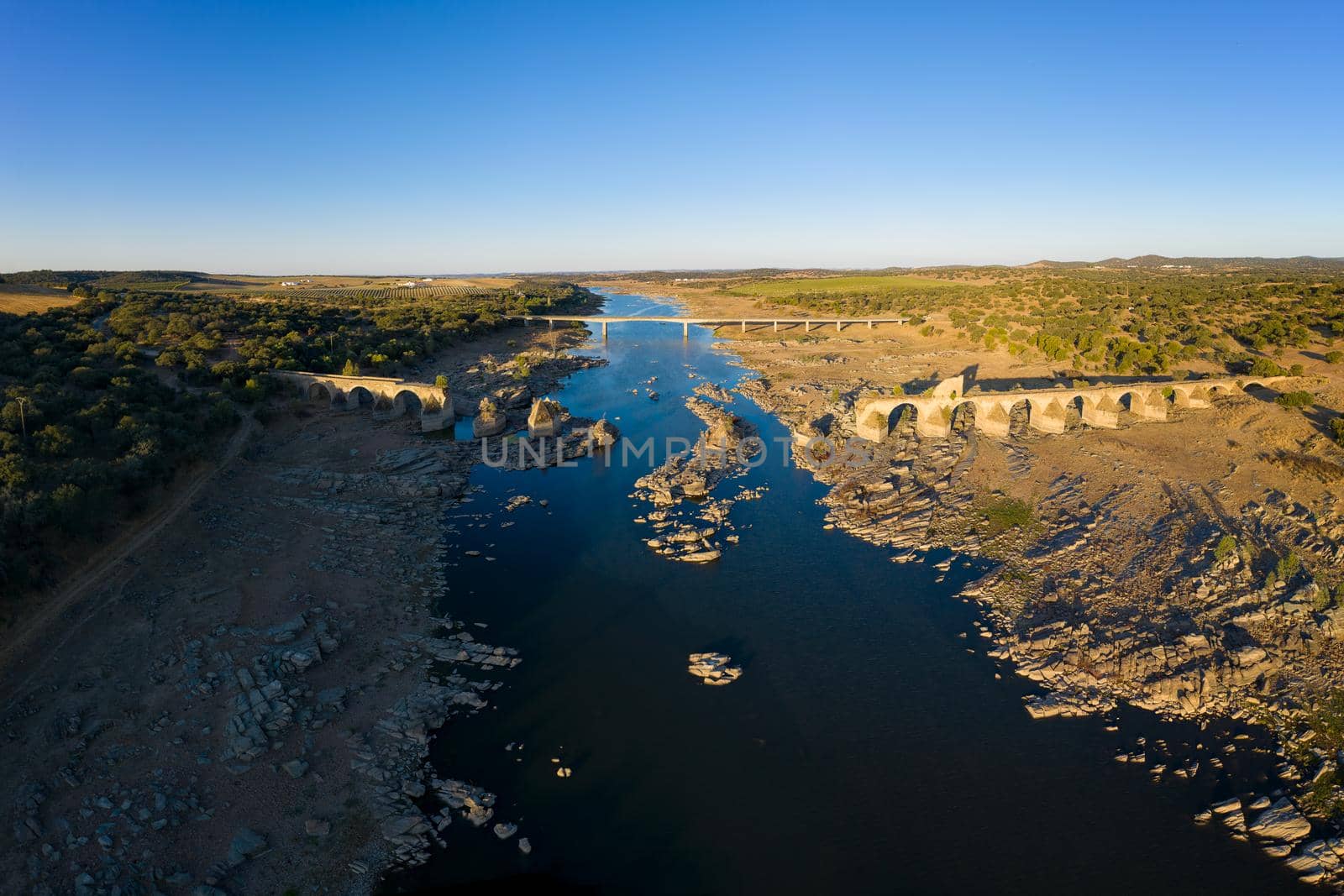 Destroyed abandoned Ajuda bridge drone aerial view, crossing the Guadiana river between Spain and Portugal