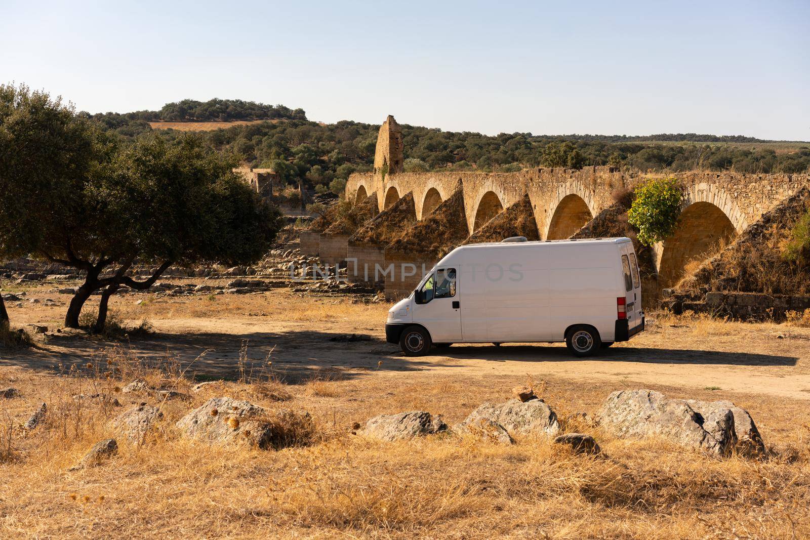 Camper van in Alentejo landscape with abandoned destroyed Ajuda bridge behind, in Portugal by Luispinaphotography