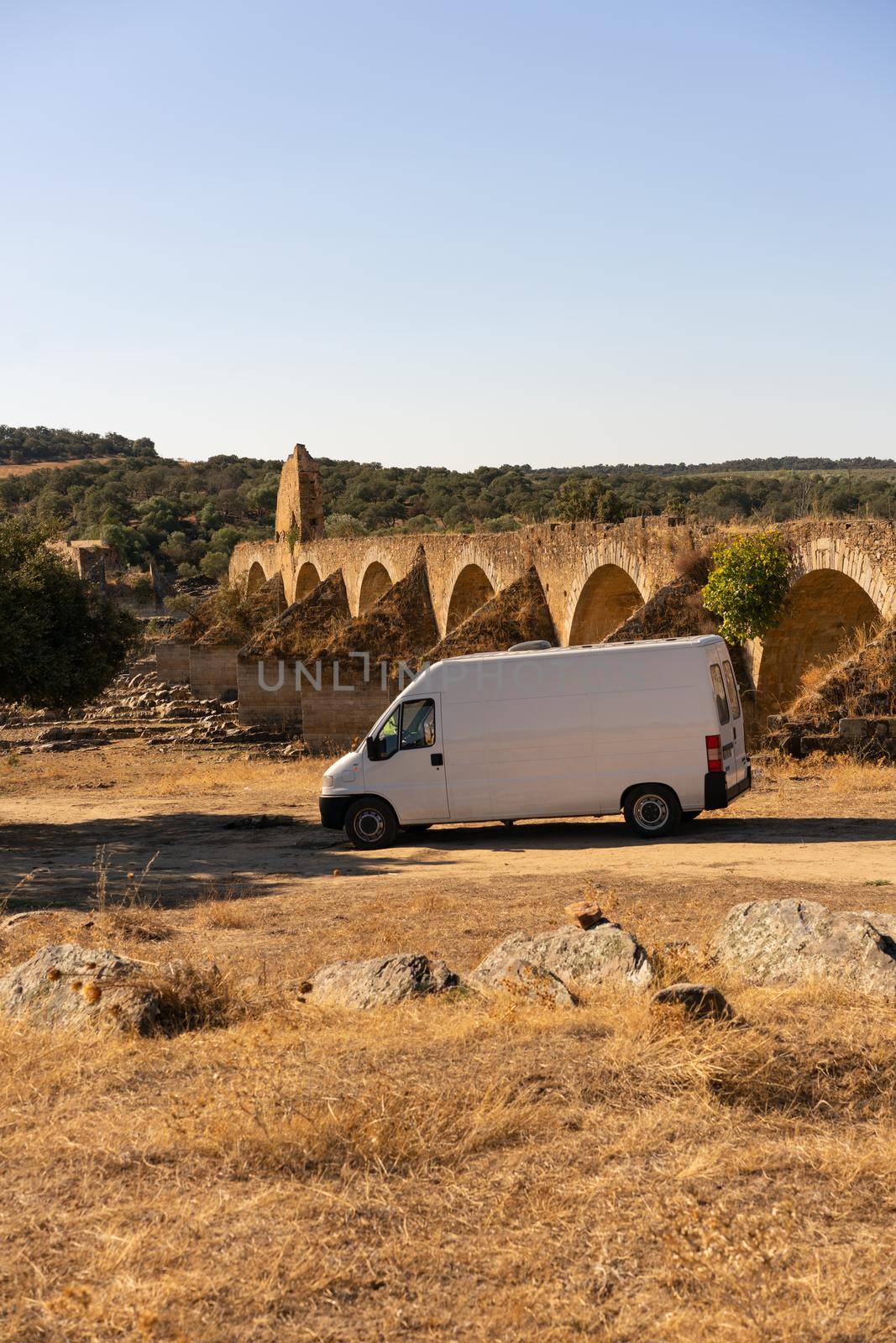 Camper van in Alentejo landscape with abandoned destroyed Ajuda bridge behind, in Portugal by Luispinaphotography