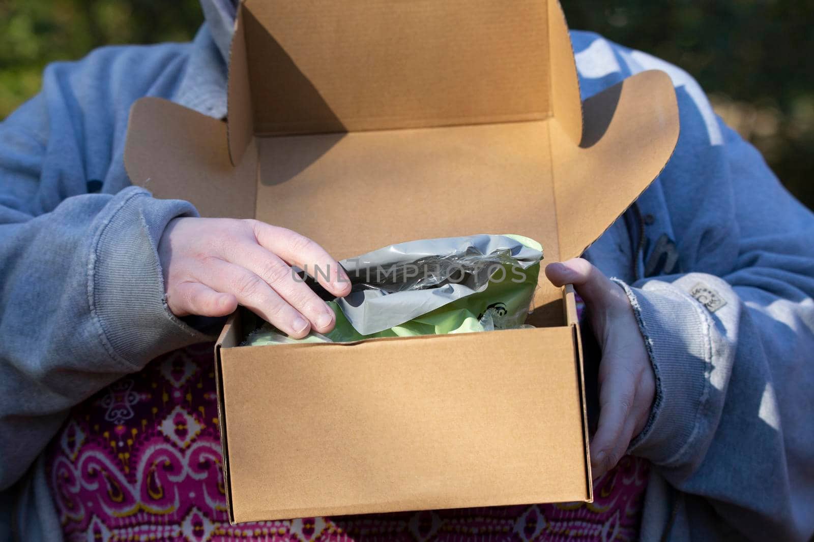 Woman opening a green plastic bag in a carboard box