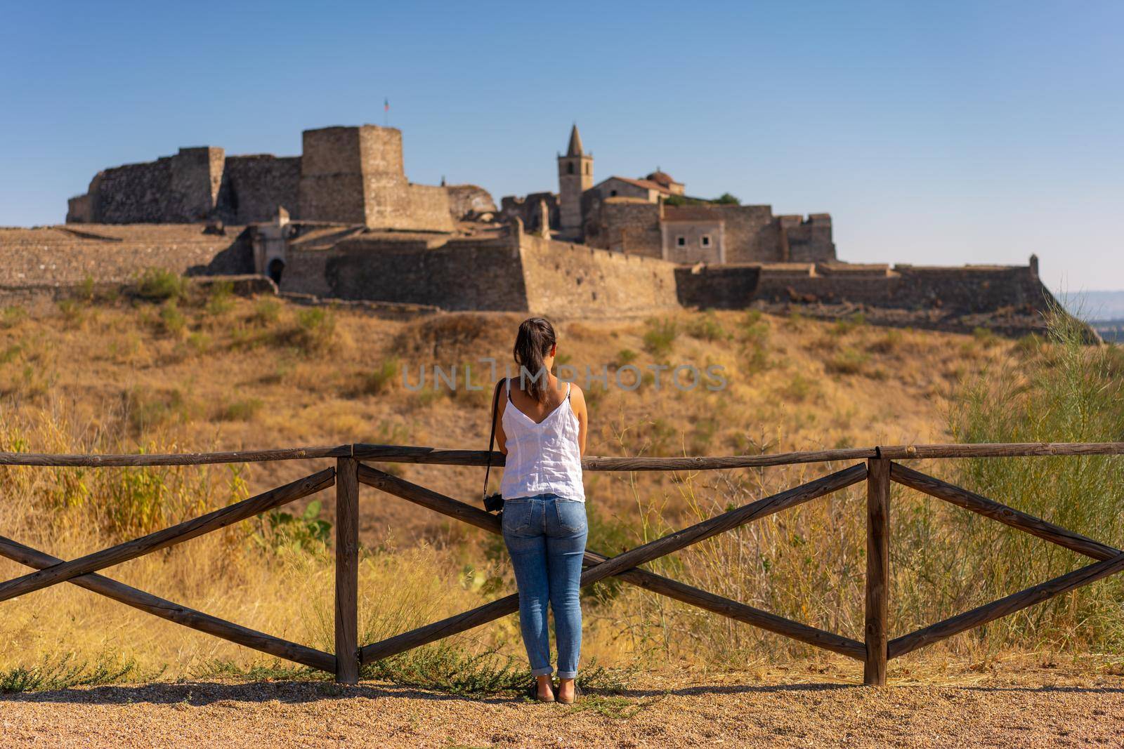 Caucasian woman looking at Juromenha castle on a summer day in Alentejo, Portugal by Luispinaphotography