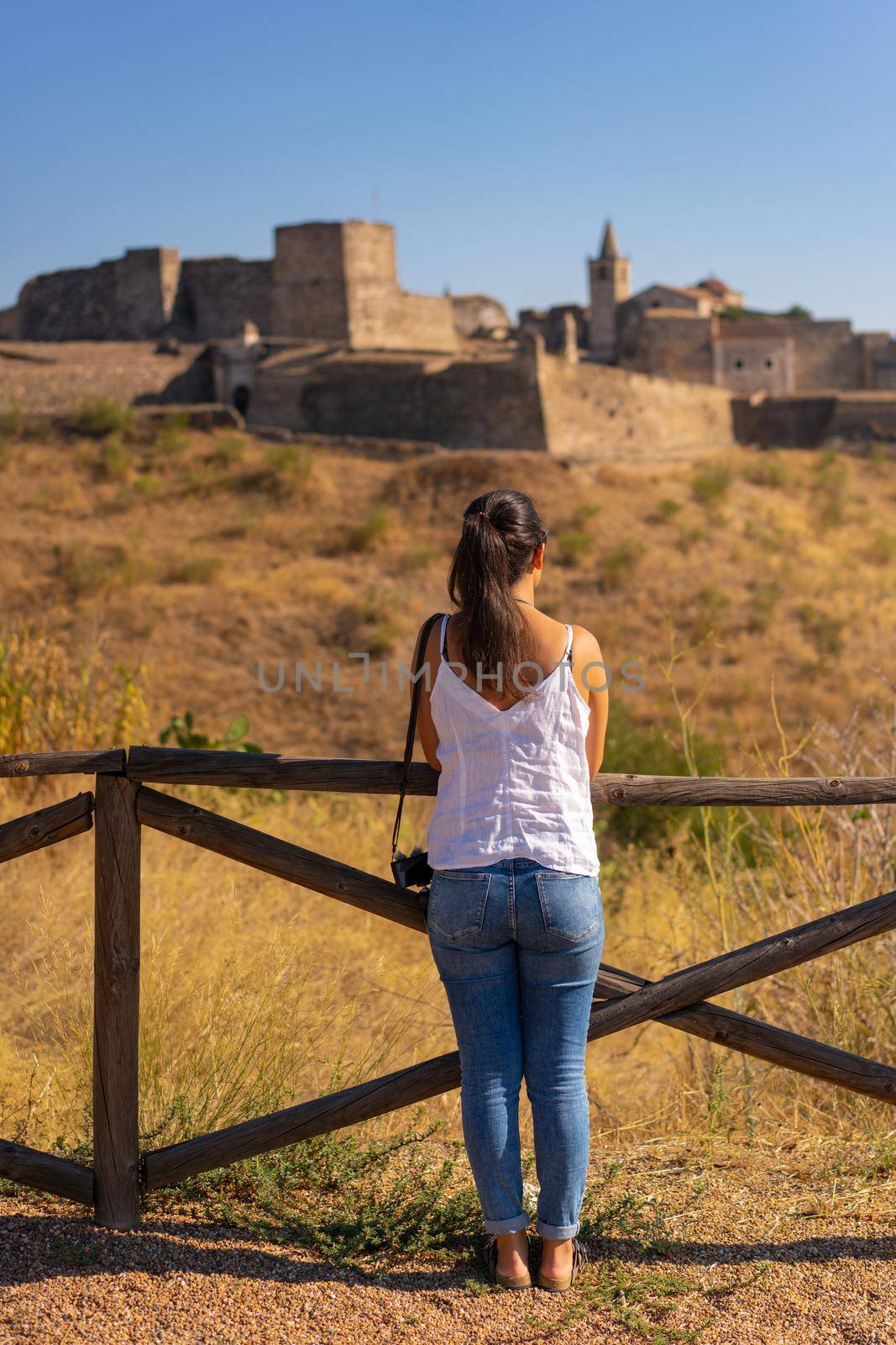 Caucasian woman looking at Juromenha castle on a summer day in Alentejo, Portugal by Luispinaphotography