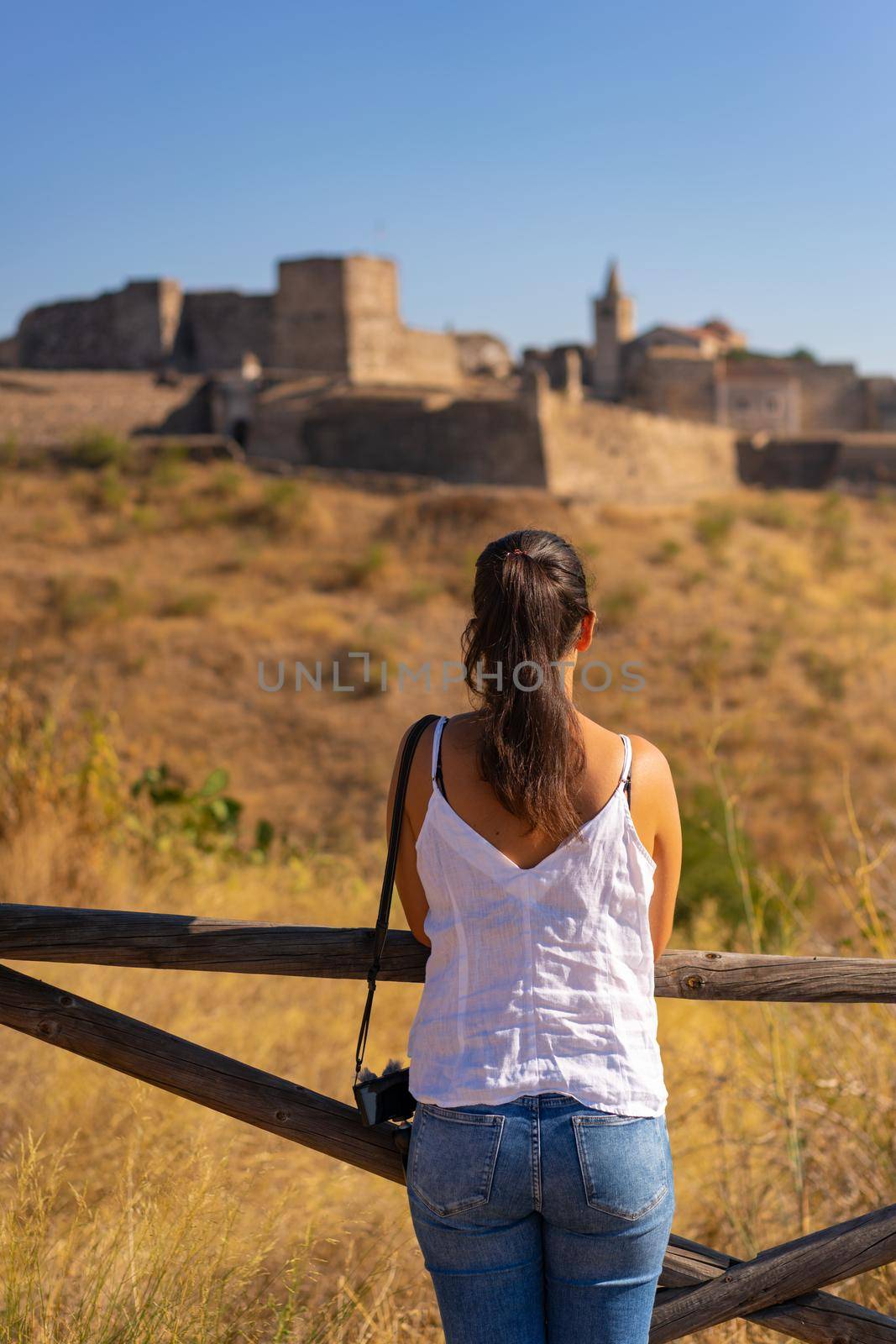 Caucasian woman looking at Juromenha castle on a summer day in Alentejo, Portugal by Luispinaphotography