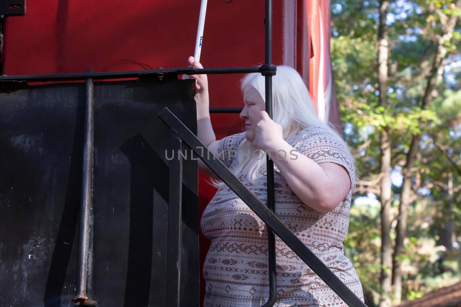 Albino woman climbing up into the caboose of a train