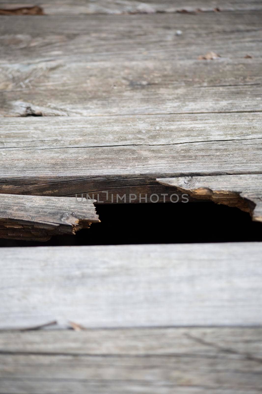 Close up of a hole in the wooden planks of an outdoor walkway