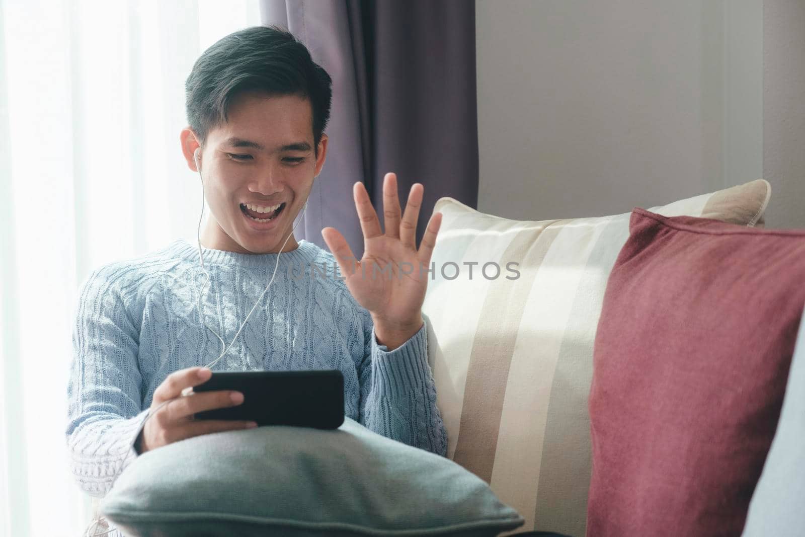 Young man making video call on laptop , waving at screen, chatting online with people who distance.
