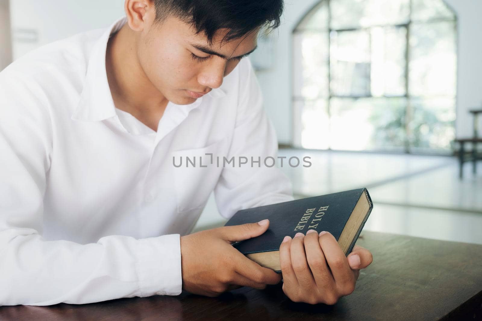 Religion, Christianity, Praying. Man praying, hands clasped together on her Bible.